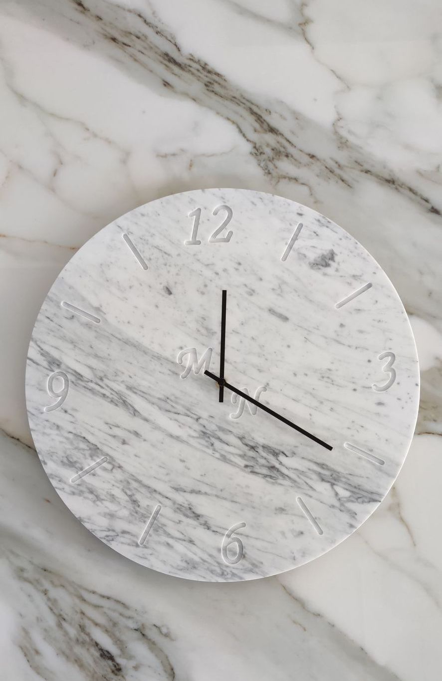 Un orologio di marmo bianco è appeso a una parete di marmo.