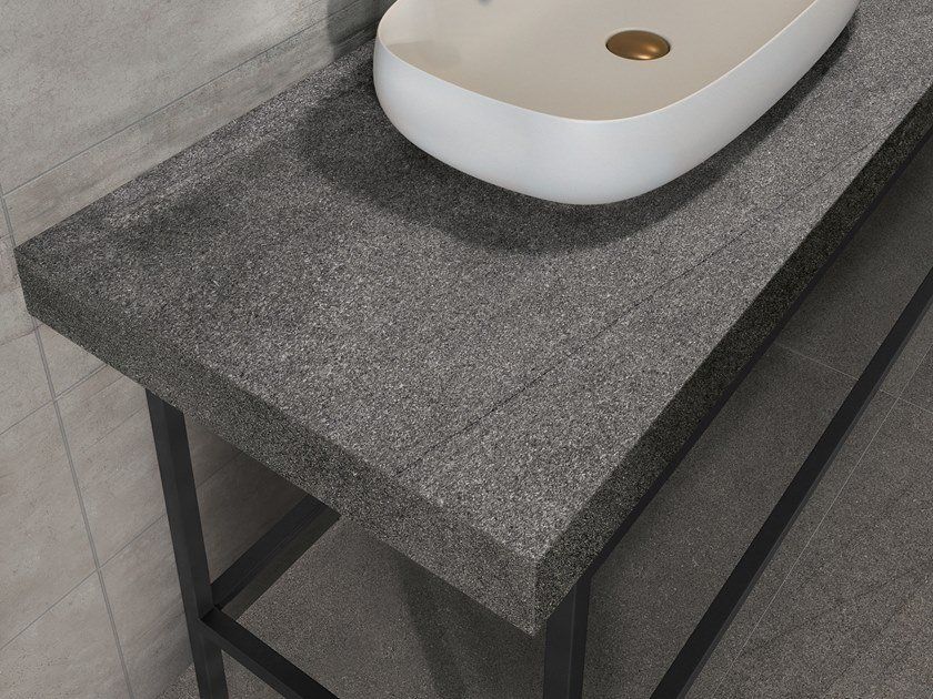 In un bagno c'è un lavandino bianco appoggiato su un ripiano grigio.