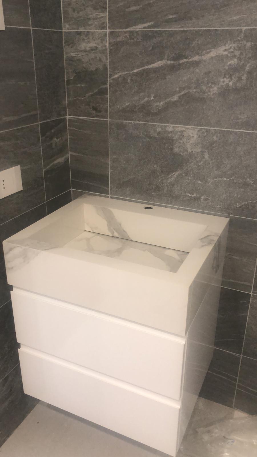Un bagno con lavandino bianco e piastrelle nere.