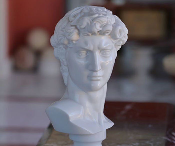 Una statua bianca raffigurante la testa di un uomo è seduta su un tavolo