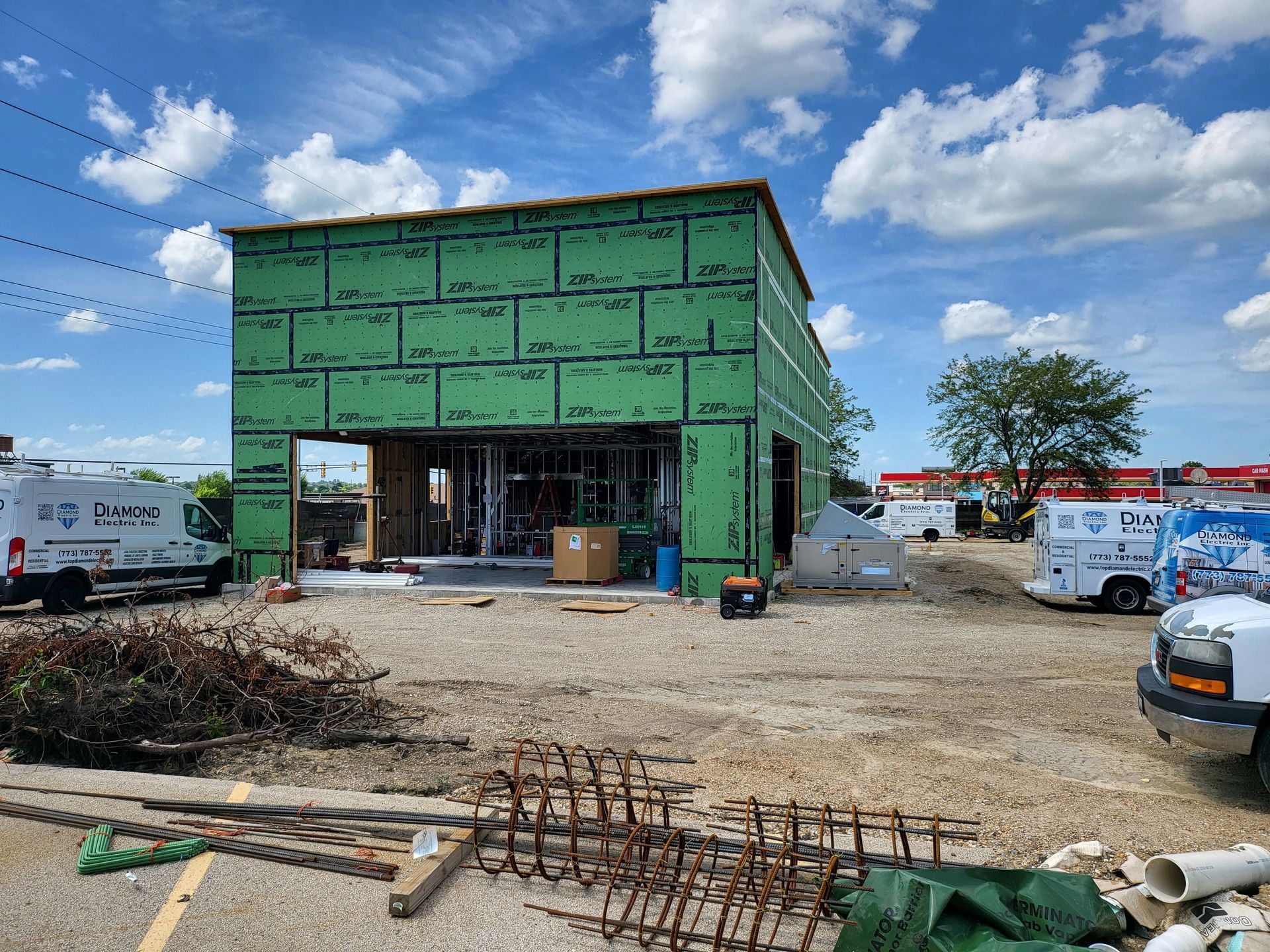 A building under construction with a lot of vehicles parked in front of it.