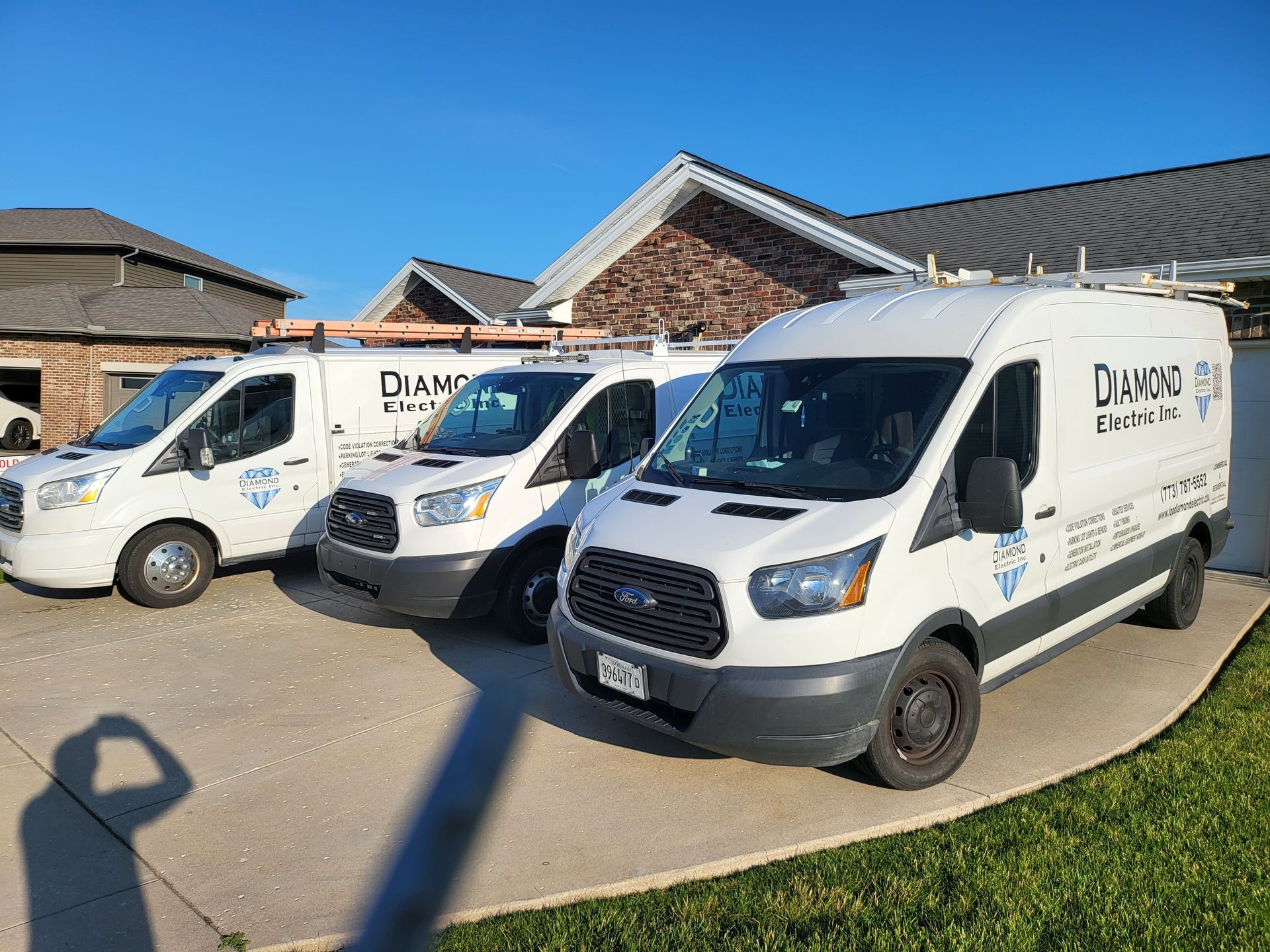 Three white vans are parked in front of a house.