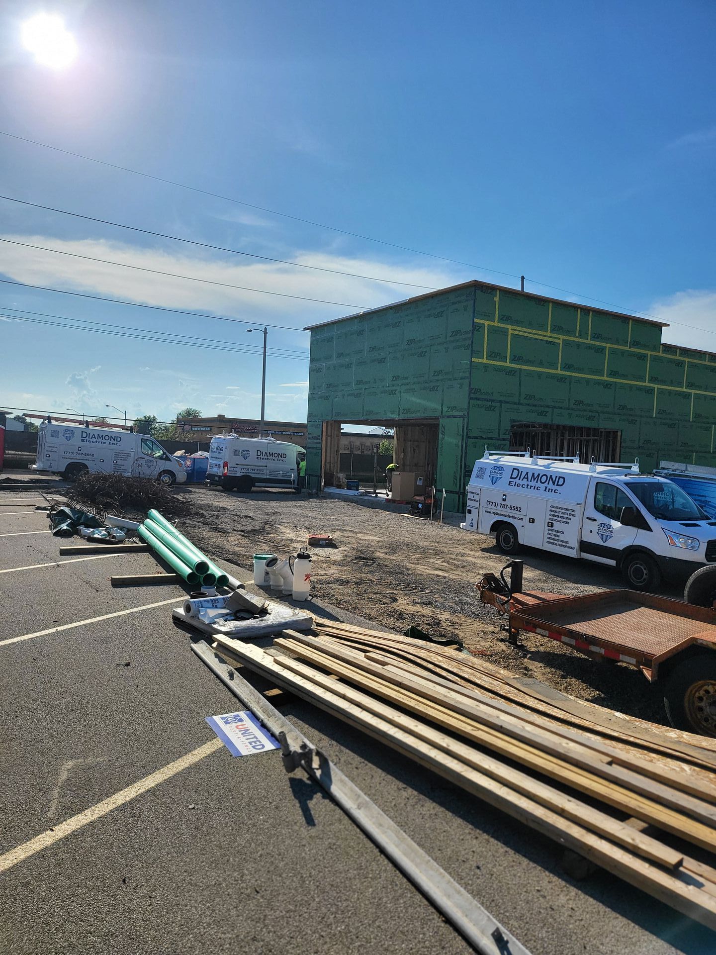 A building under construction with a lot of trucks parked in front of it.