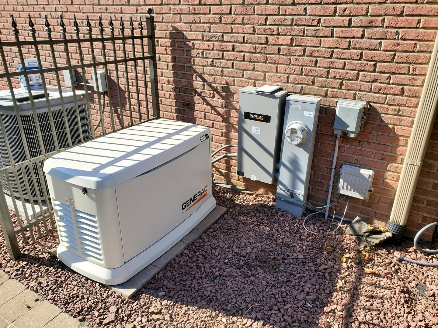 A white generator is sitting in front of a brick building.