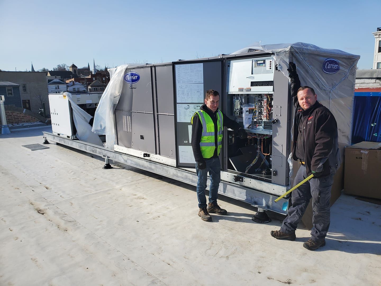 Two men are standing next to a large container on a roof.