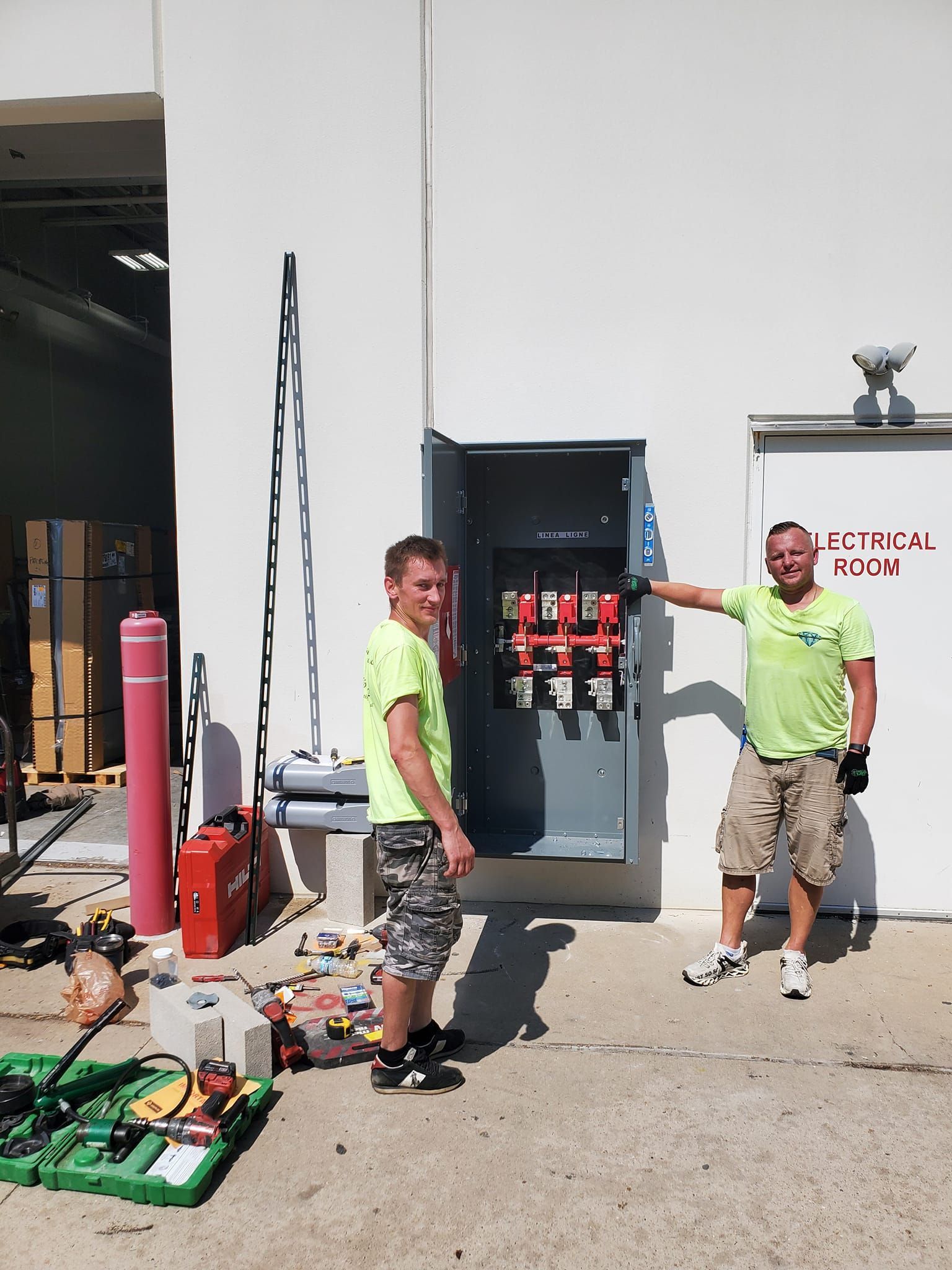 Two men are standing in front of a building with a sign that says ' electrical ' on it