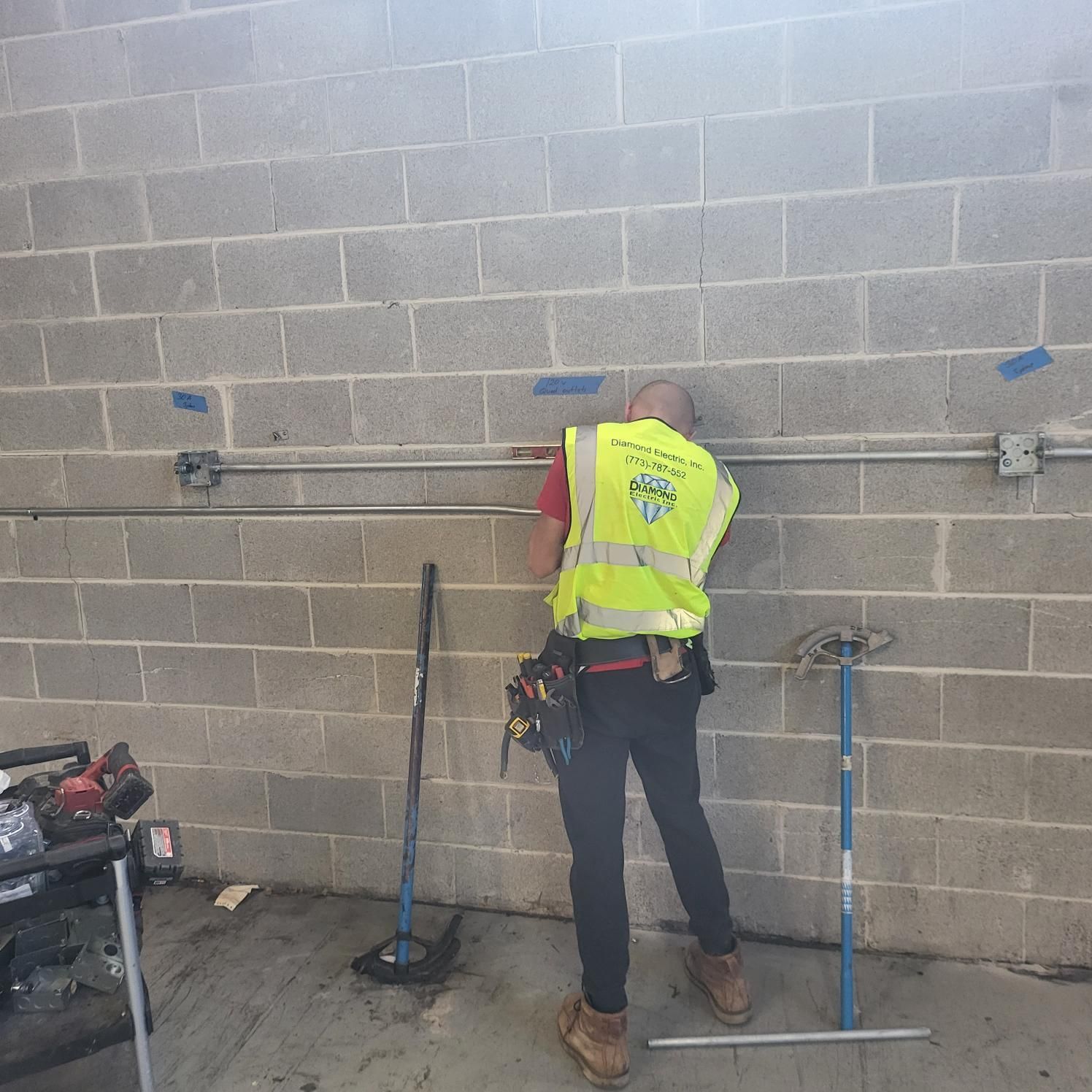 A man in a yellow vest is working on a brick wall