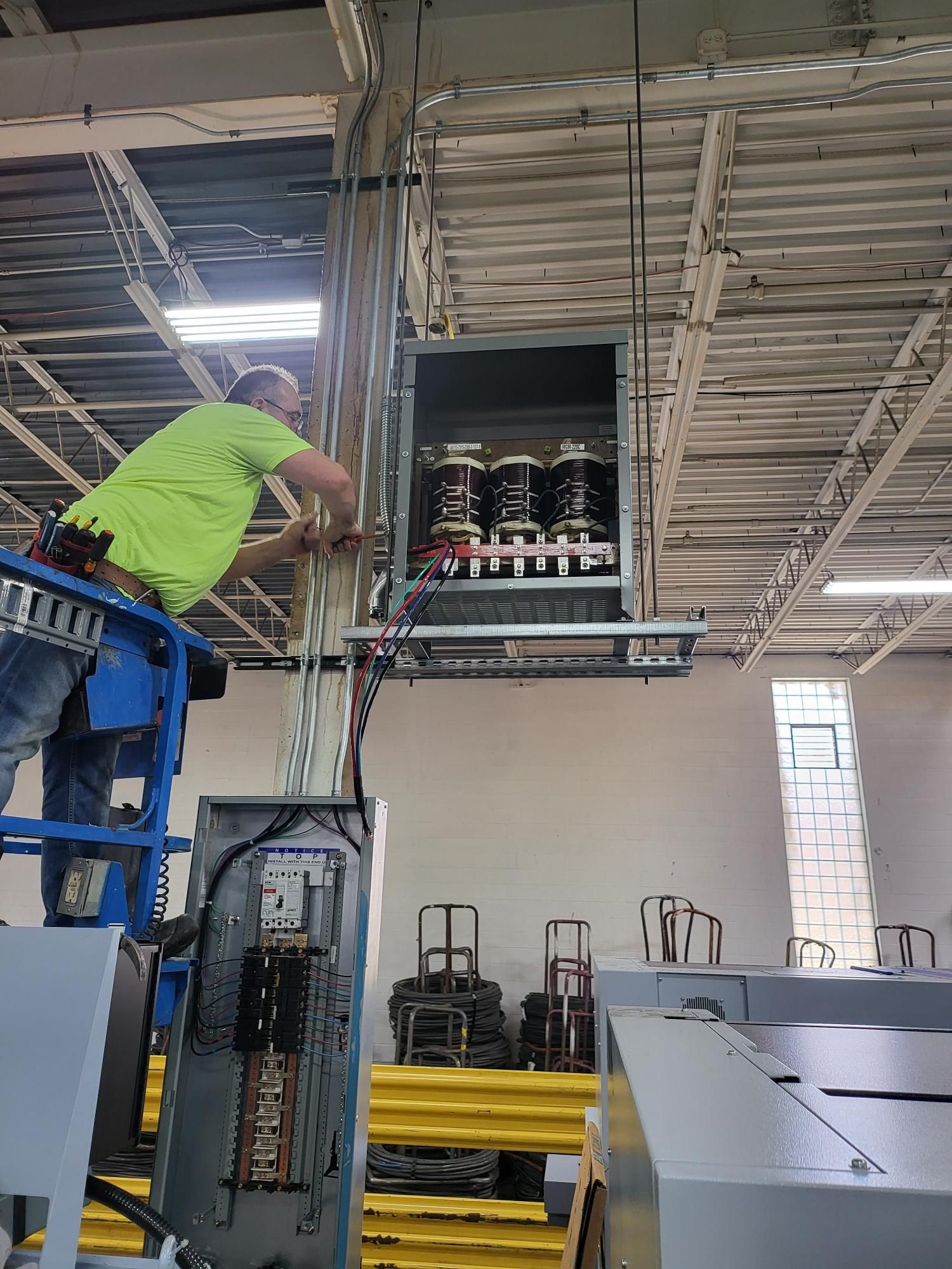 A man is working on an electrical box in a building.