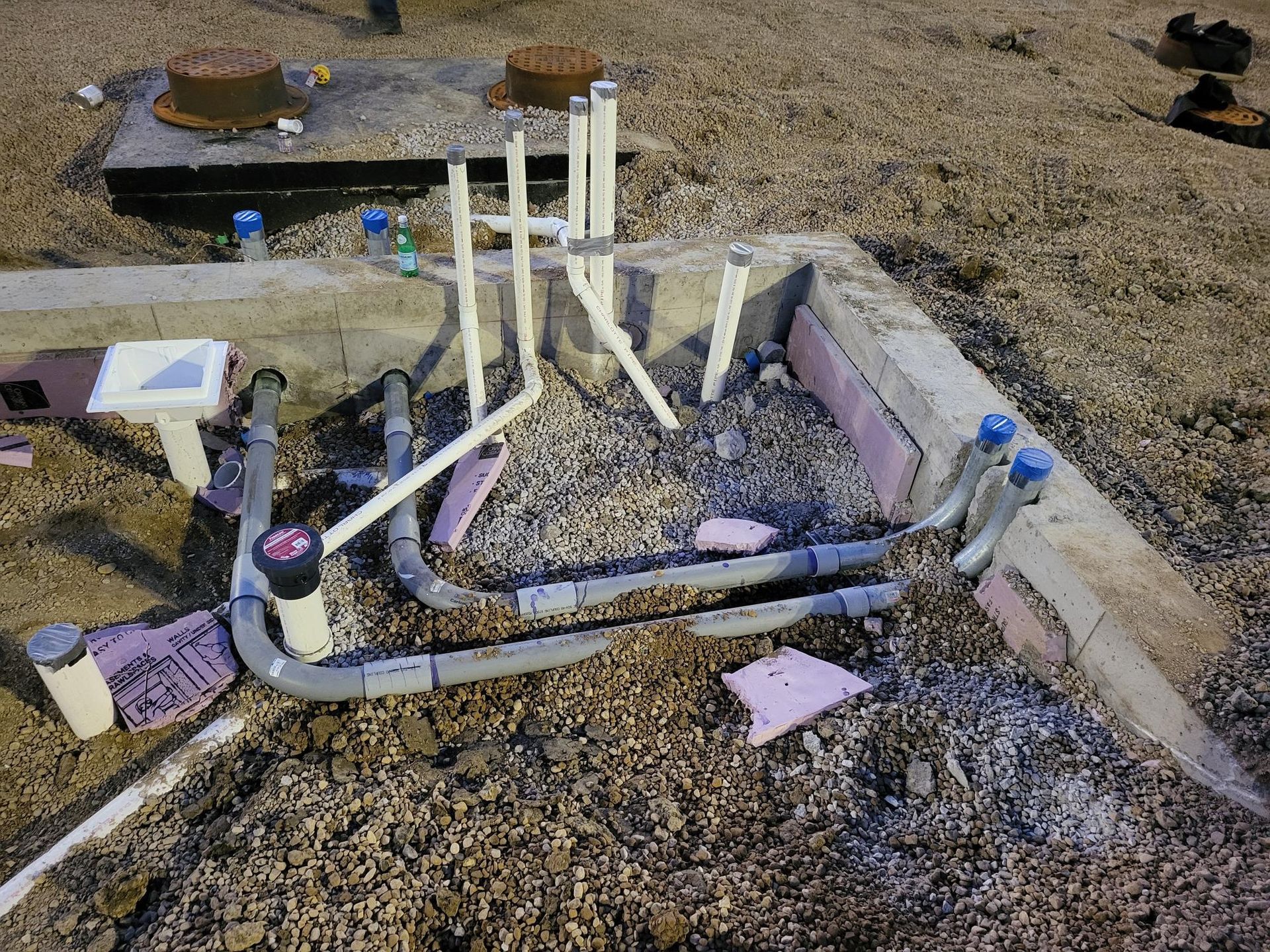 A bunch of pipes are laying in the dirt on the ground