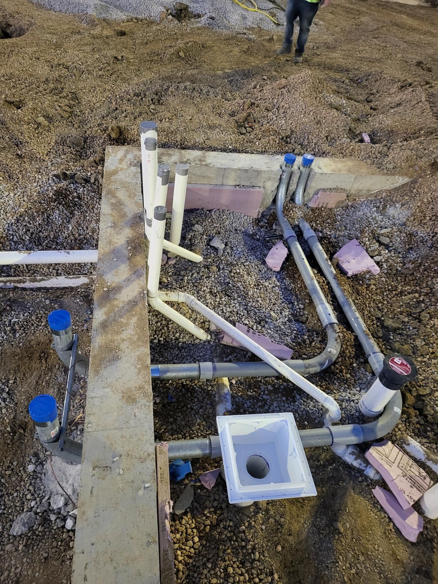 A bunch of pipes are laying in the dirt on the ground.