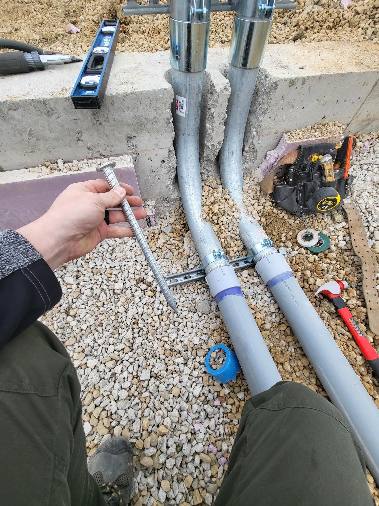 A person is holding a screw in their hand while working on a pipe.