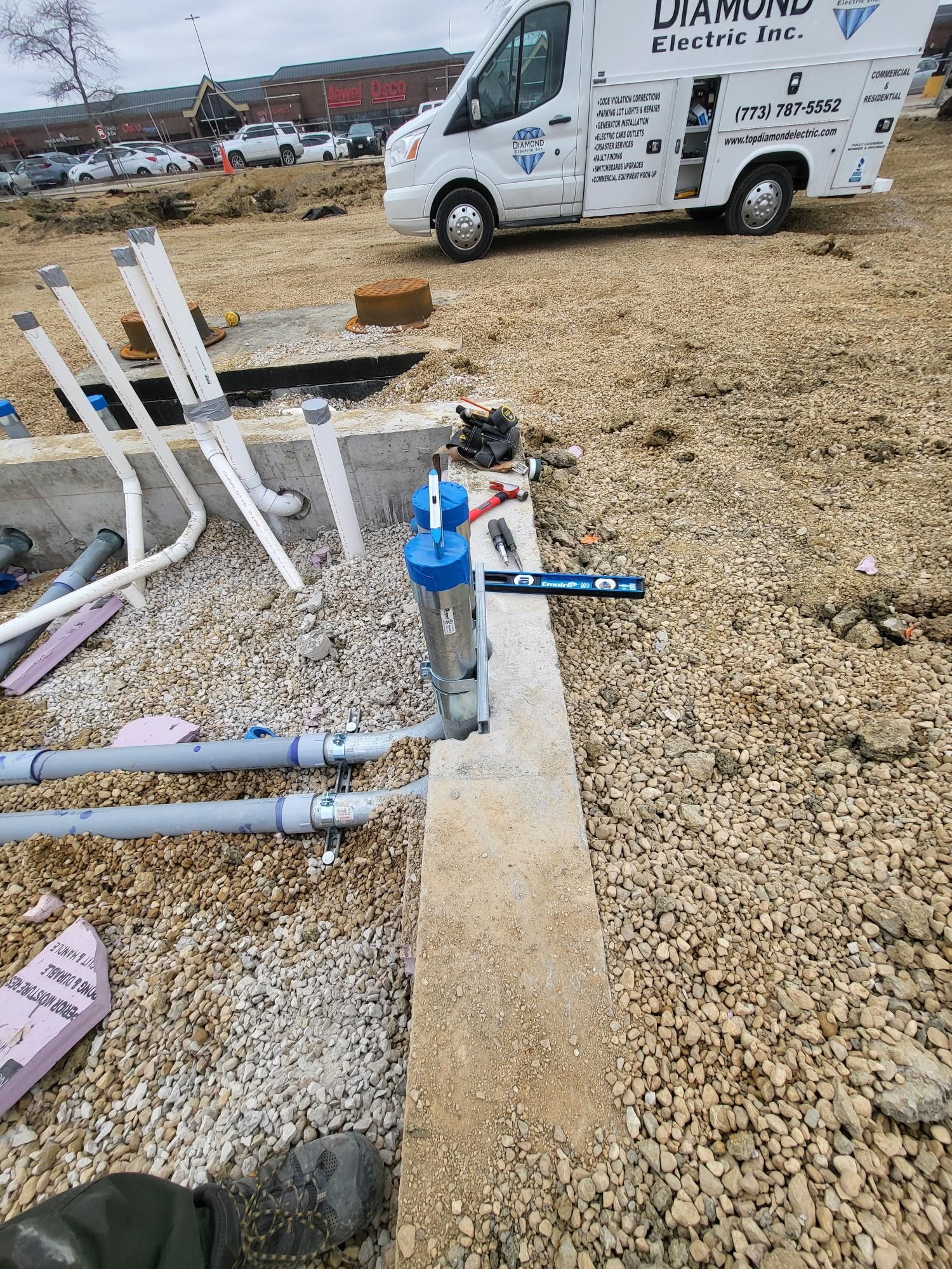A white van is parked in a gravel lot.
