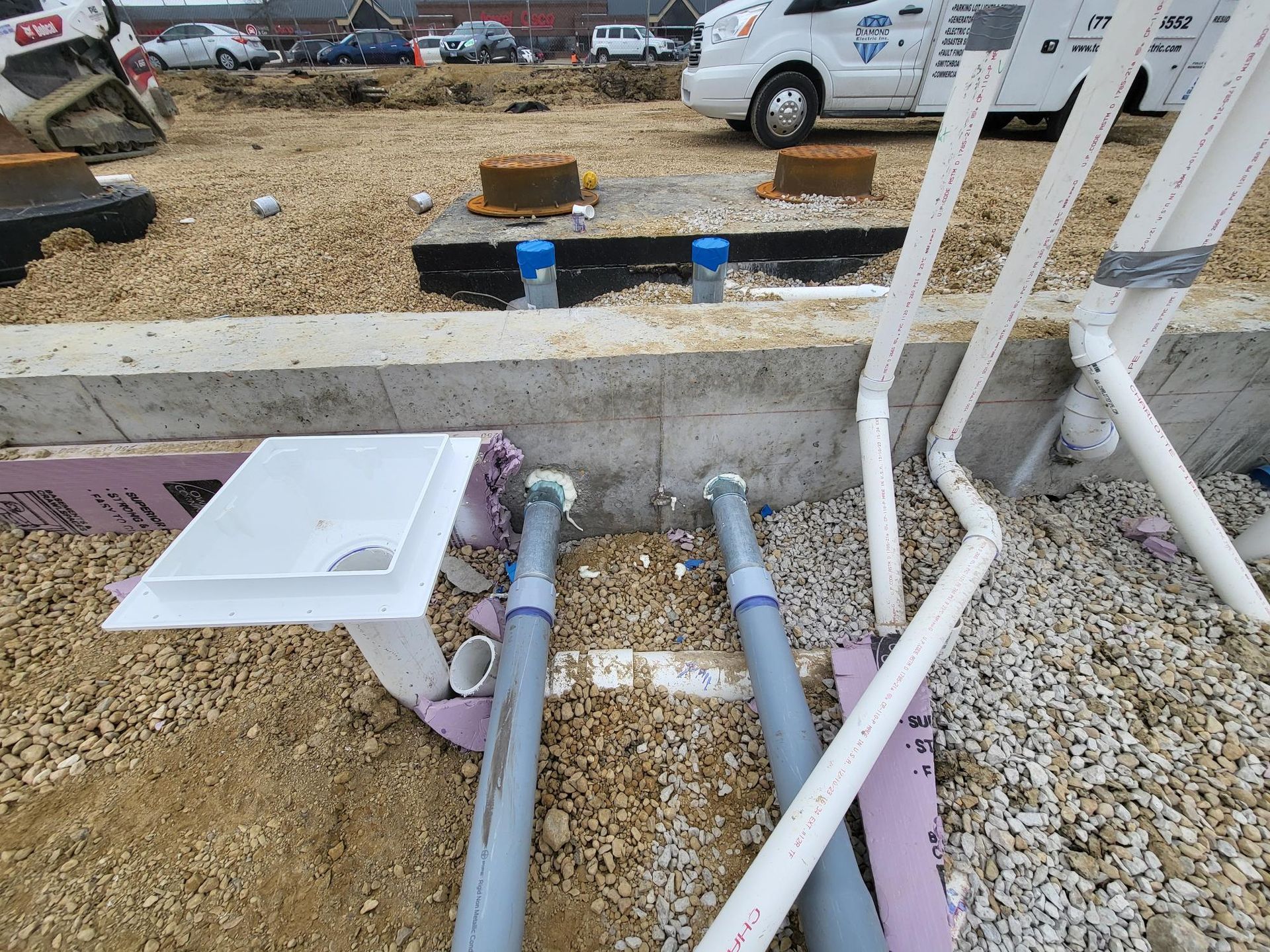 A bunch of pipes are laying in the dirt on a construction site.