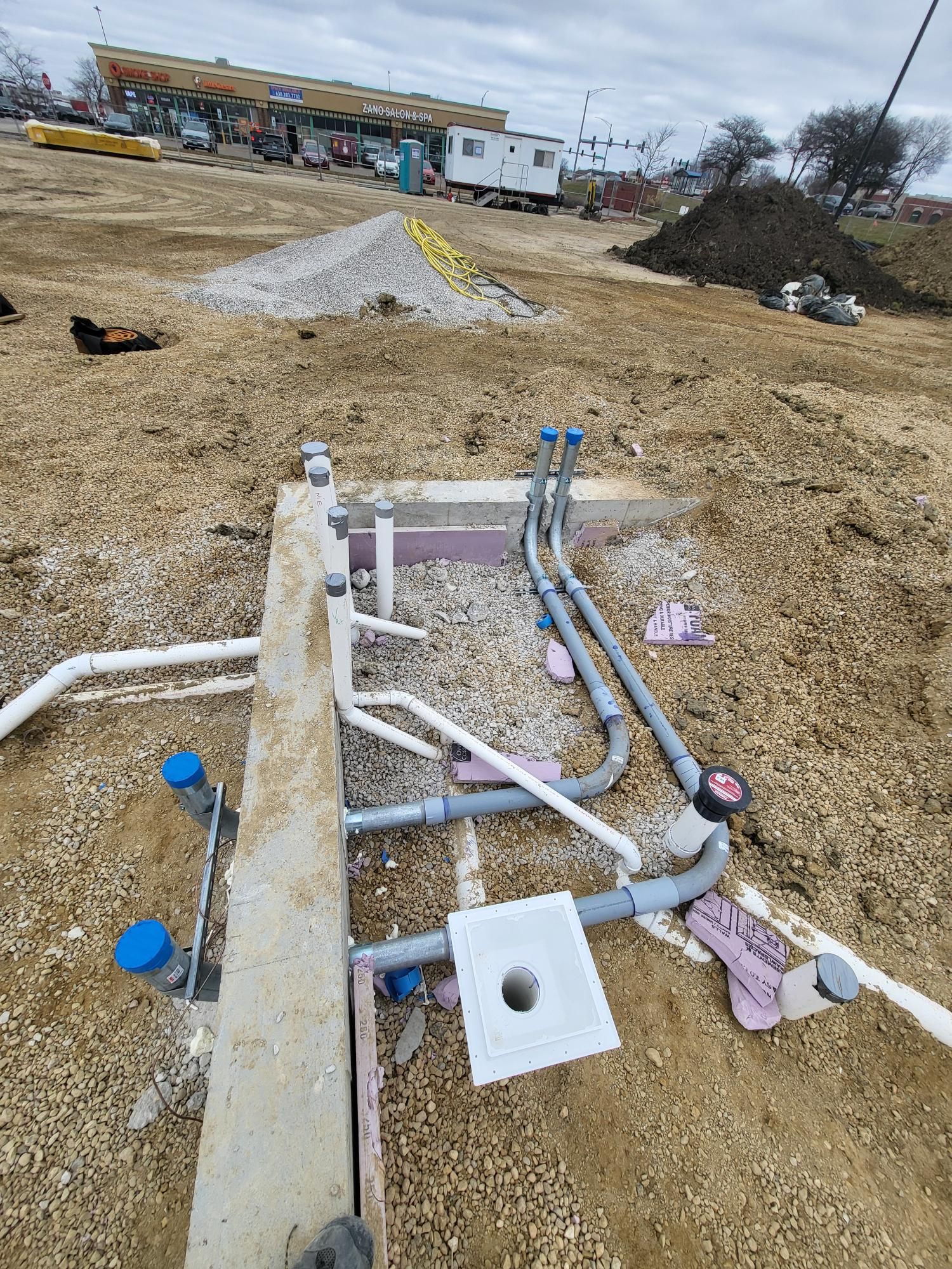A bunch of pipes are laying in the dirt on a construction site.