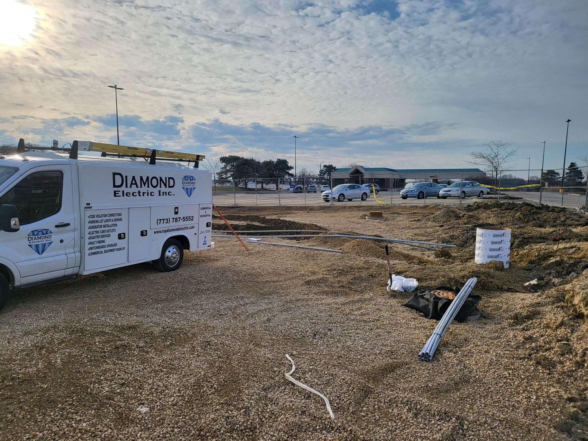 A white van is parked in a gravel lot.