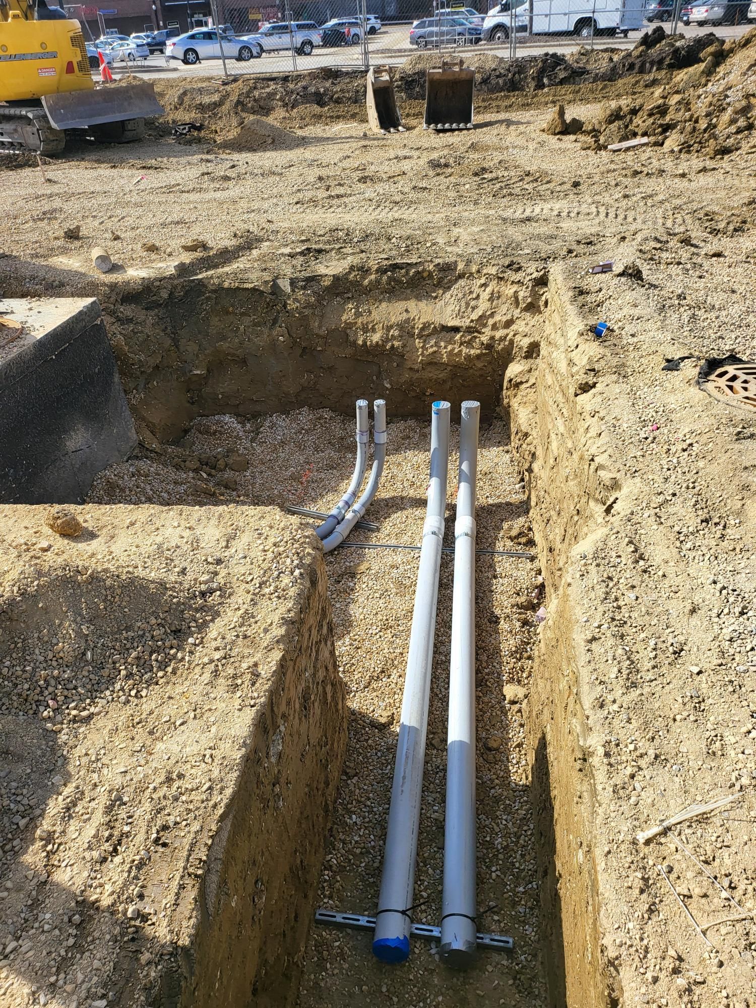 A bunch of pipes are laying in the dirt on a construction site.