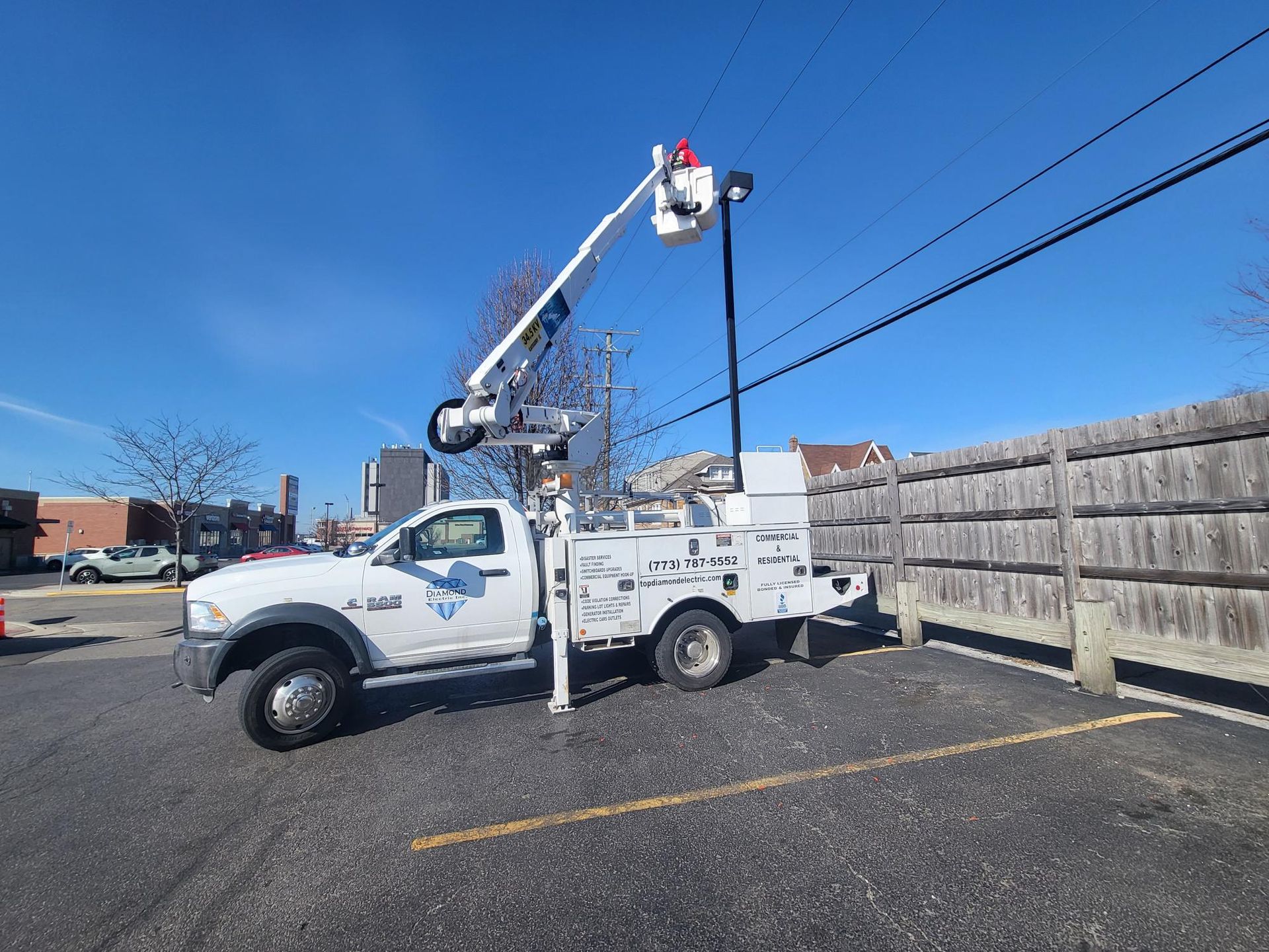 A white truck with a bucket on top of it is parked in a parking lot.