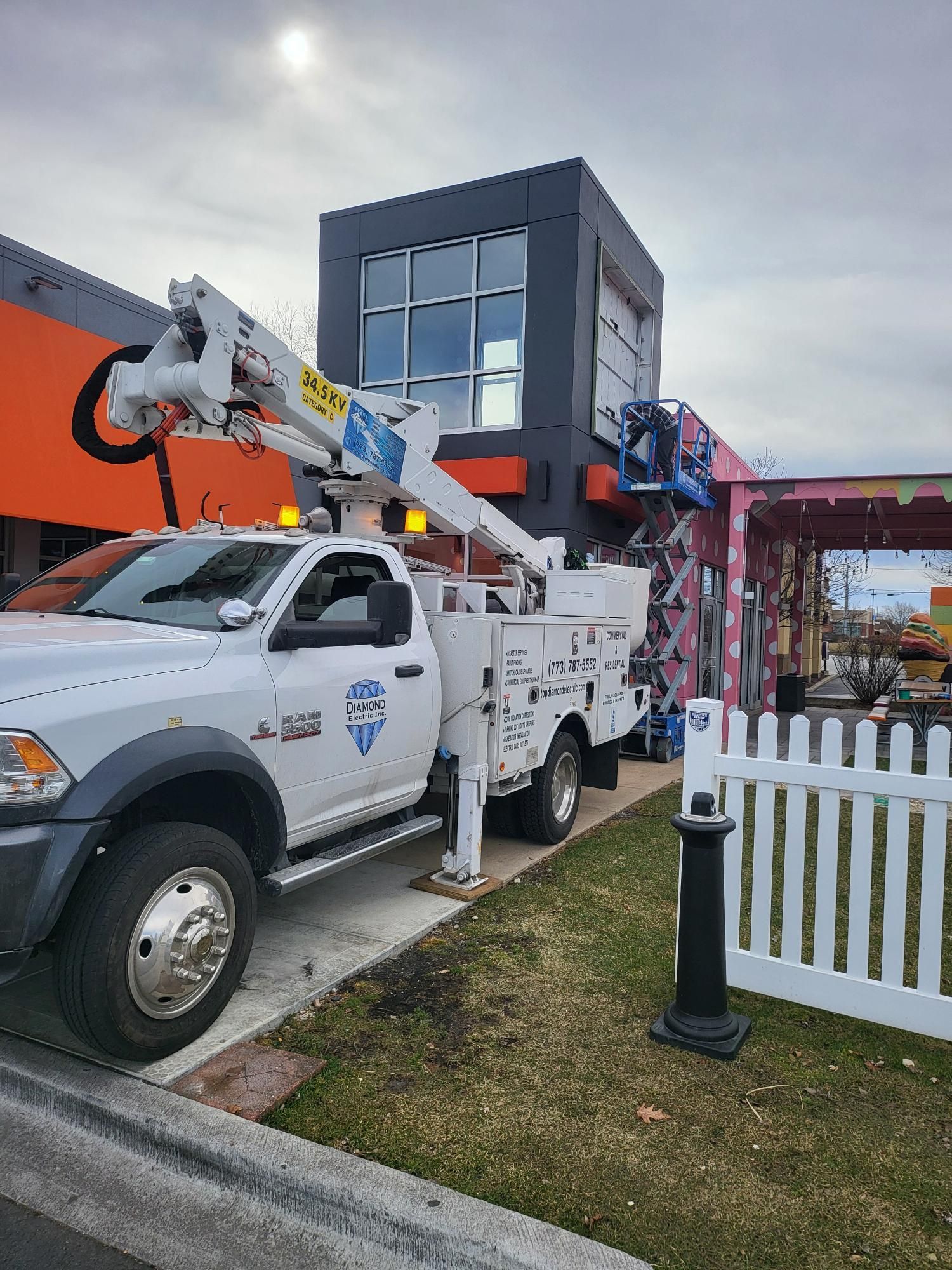 A white truck with a crane on top of it is parked in front of a building.