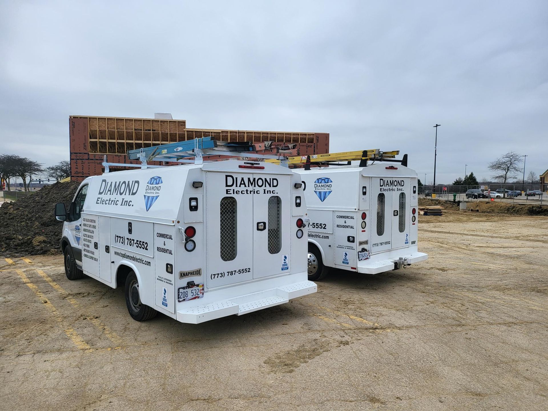 Two white vans are parked next to each other in a parking lot.