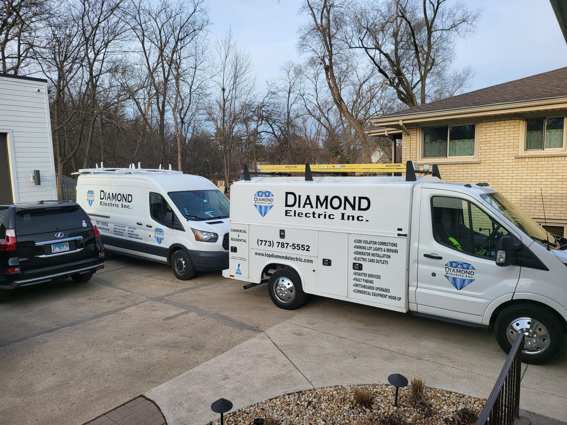 Two diamond electric vans are parked in front of a house.