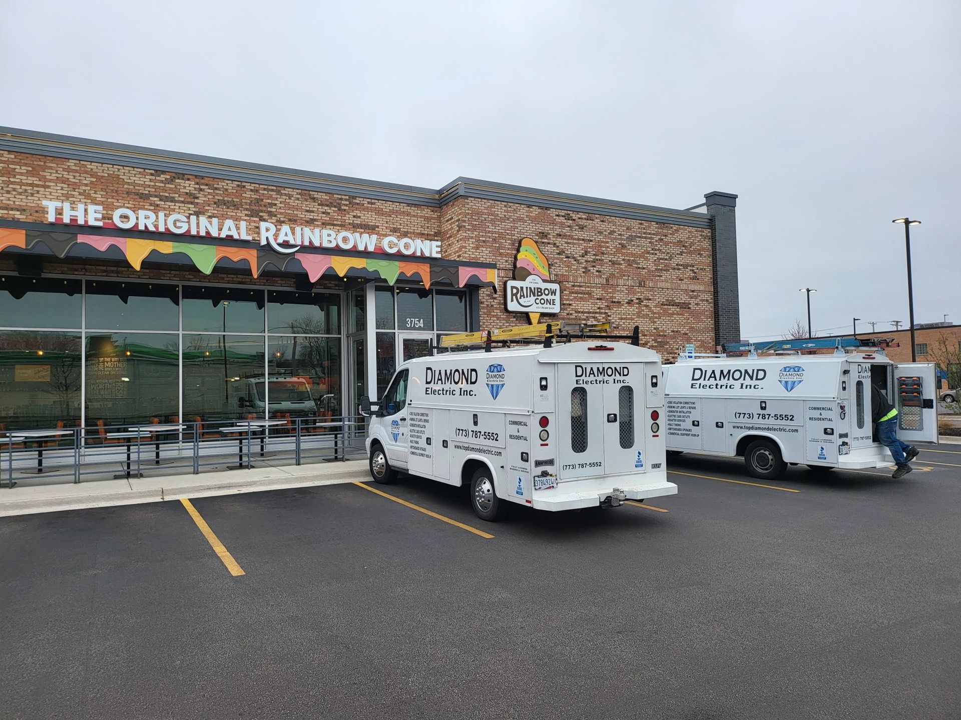 Two white vans are parked in front of a building.