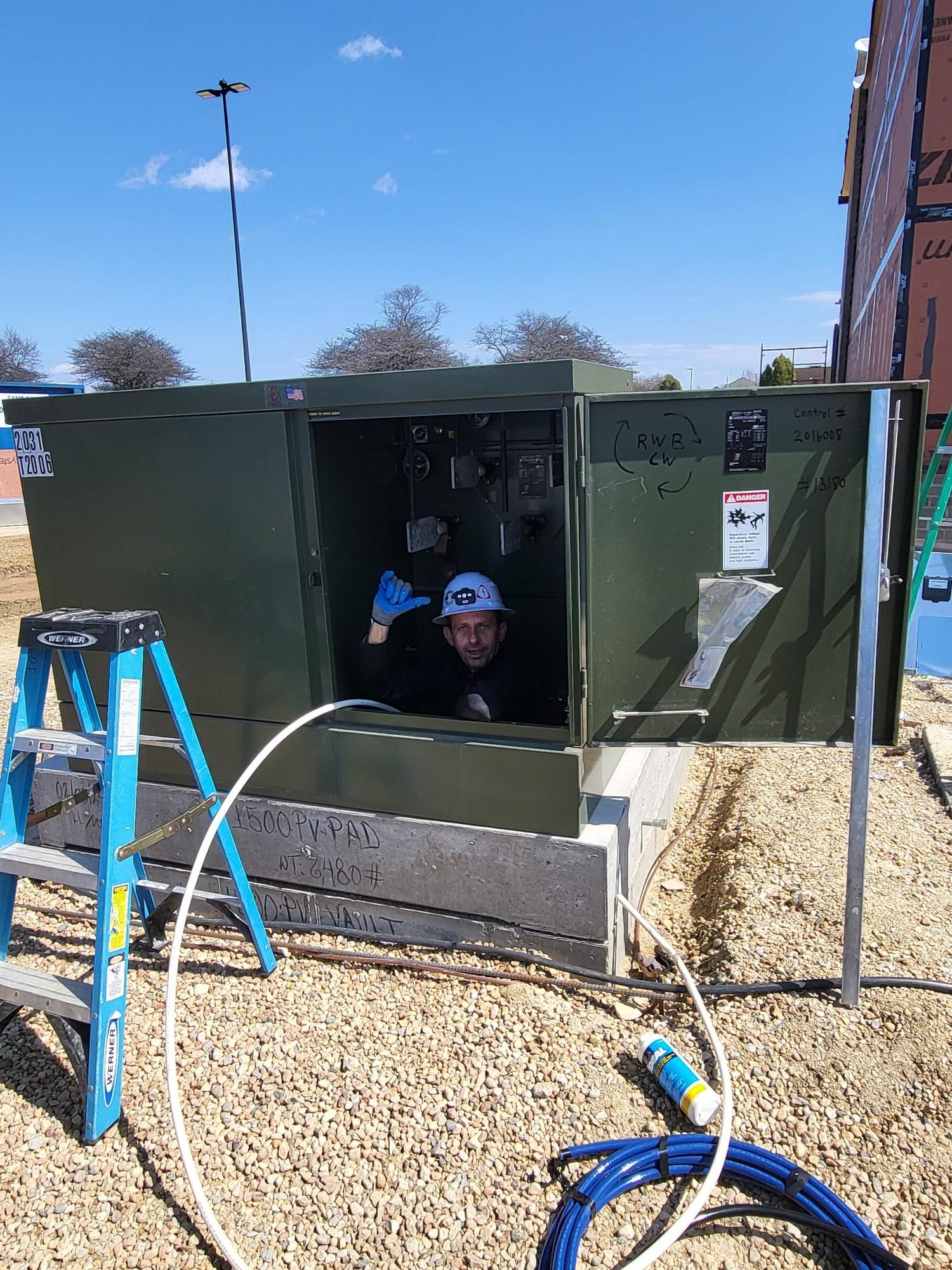 A man is peeking out of a box with a ladder next to it.