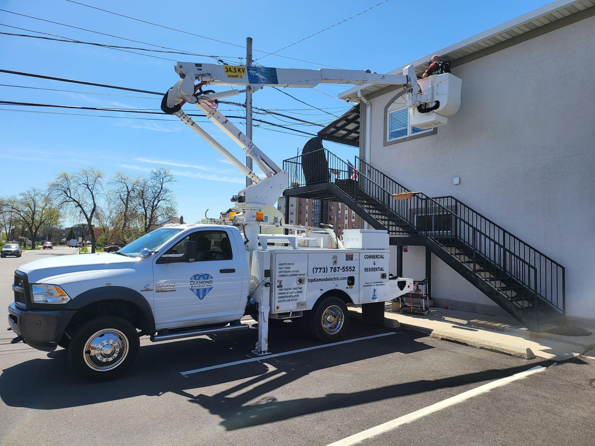 A white truck with a crane on the back is parked in front of a building.