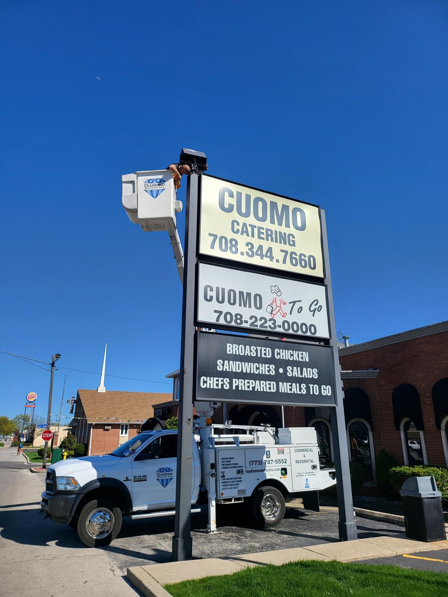 A white truck is parked in front of a cuomo catering sign.