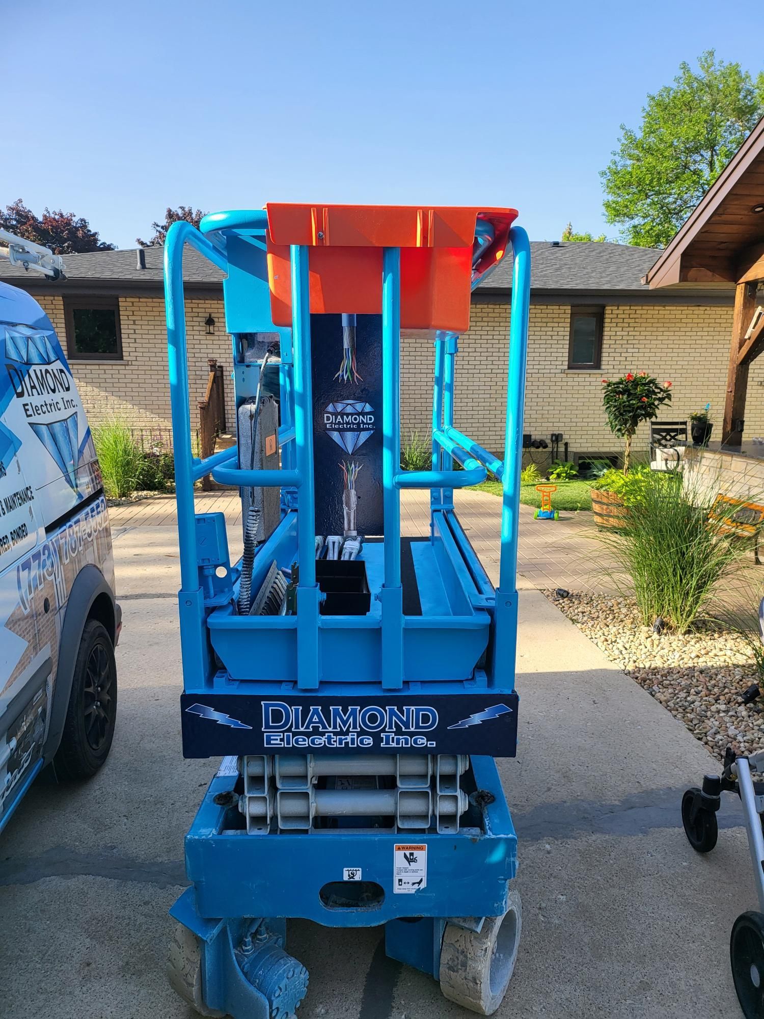 A blue scissor lift is parked in front of a house.