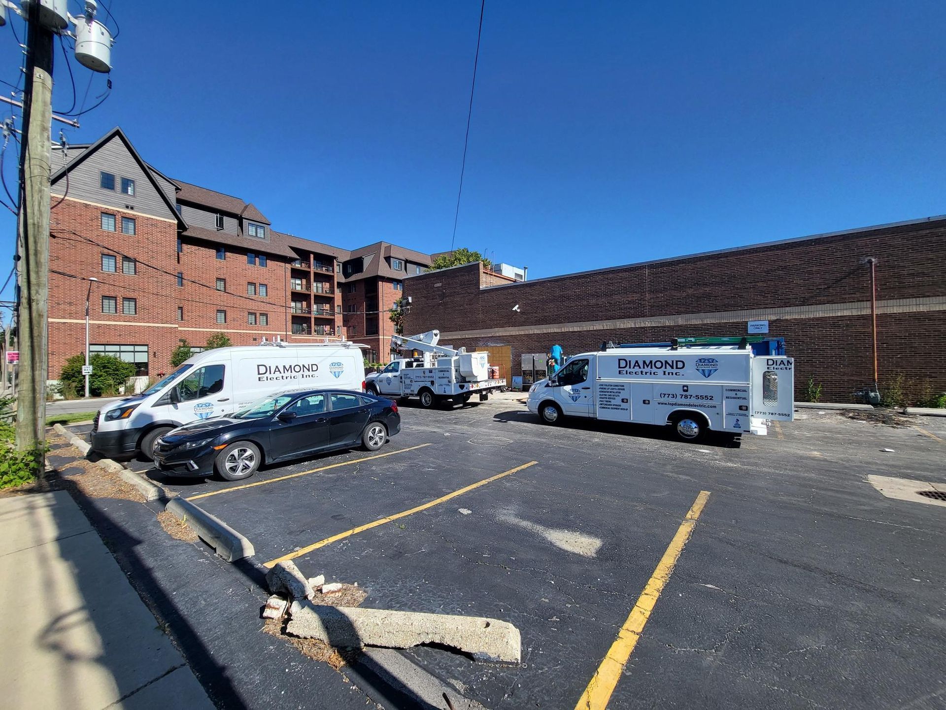 A bunch of vans are parked in a parking lot in front of a building.