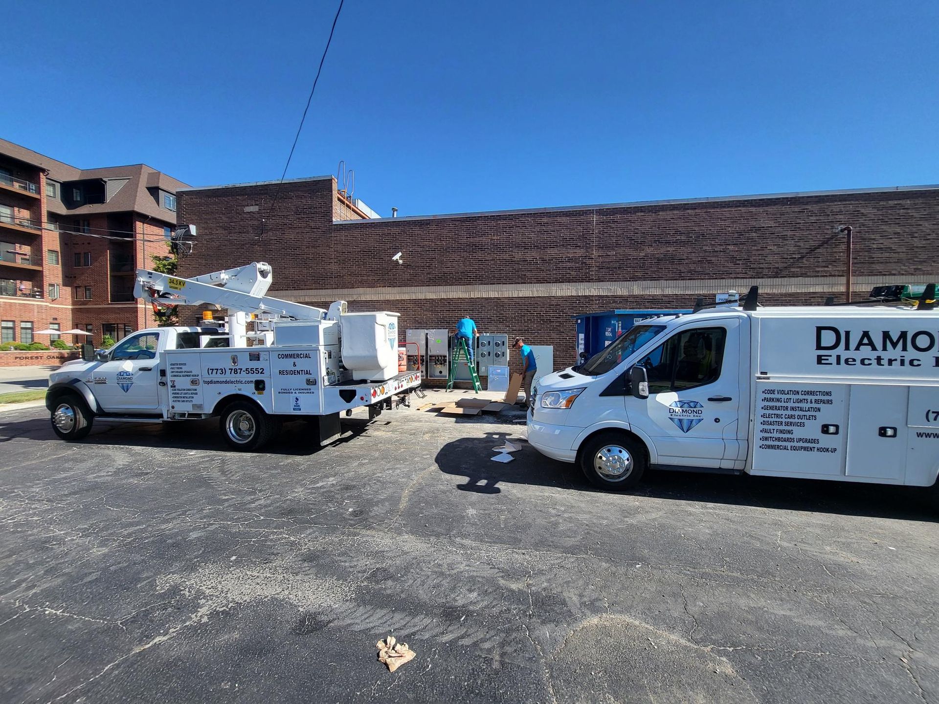 Two white vans are parked in a parking lot in front of a building.