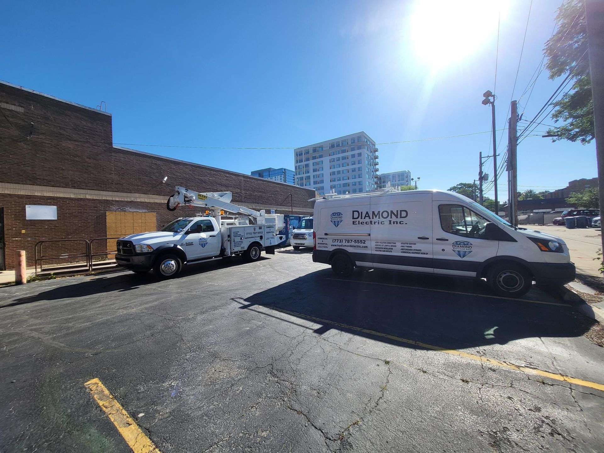 Two white vans are parked in a parking lot in front of a building.