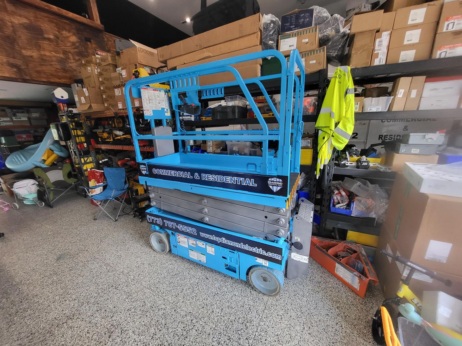 A blue scissor lift is sitting in a garage.