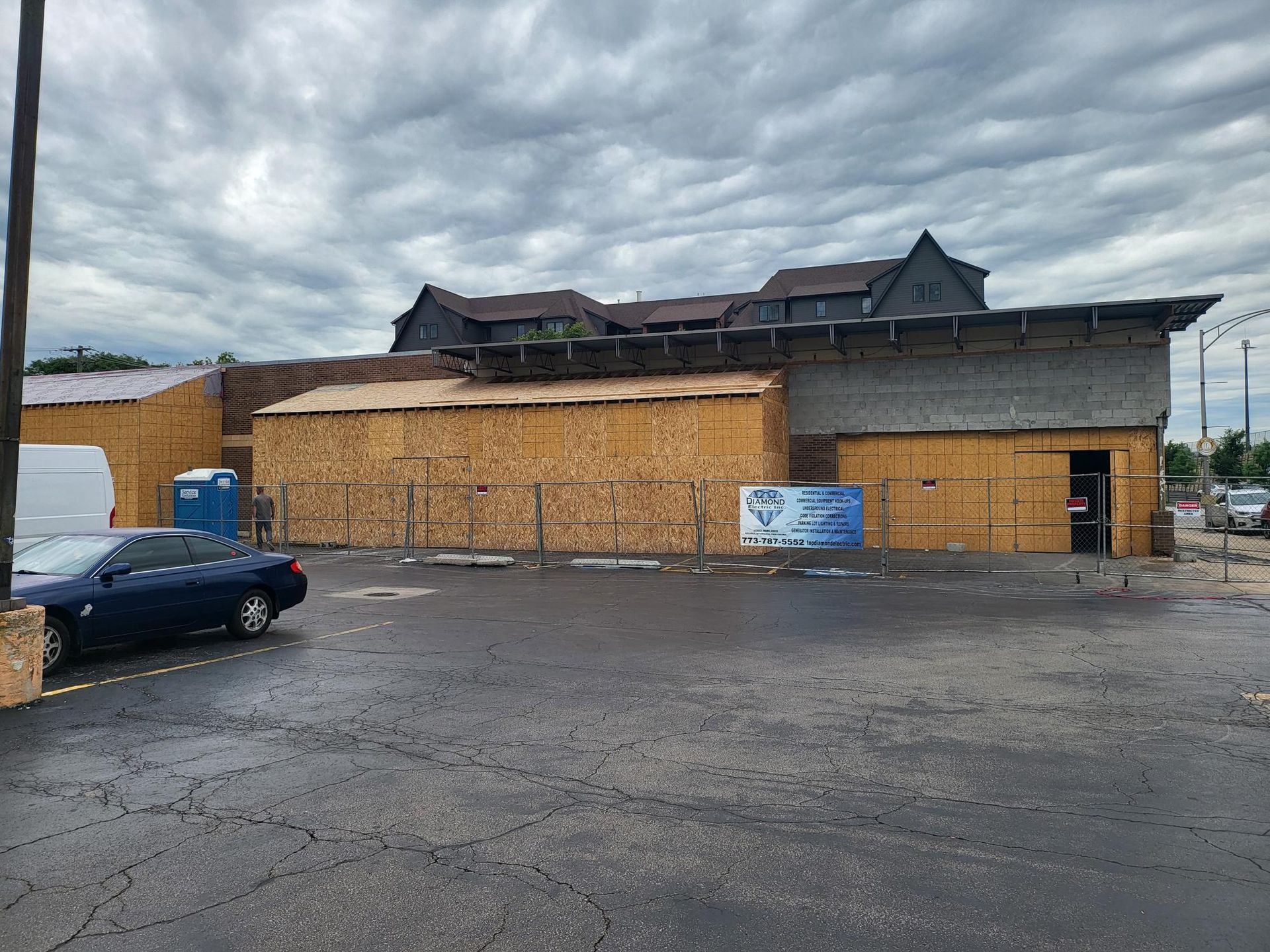 A car is parked in front of a building under construction.