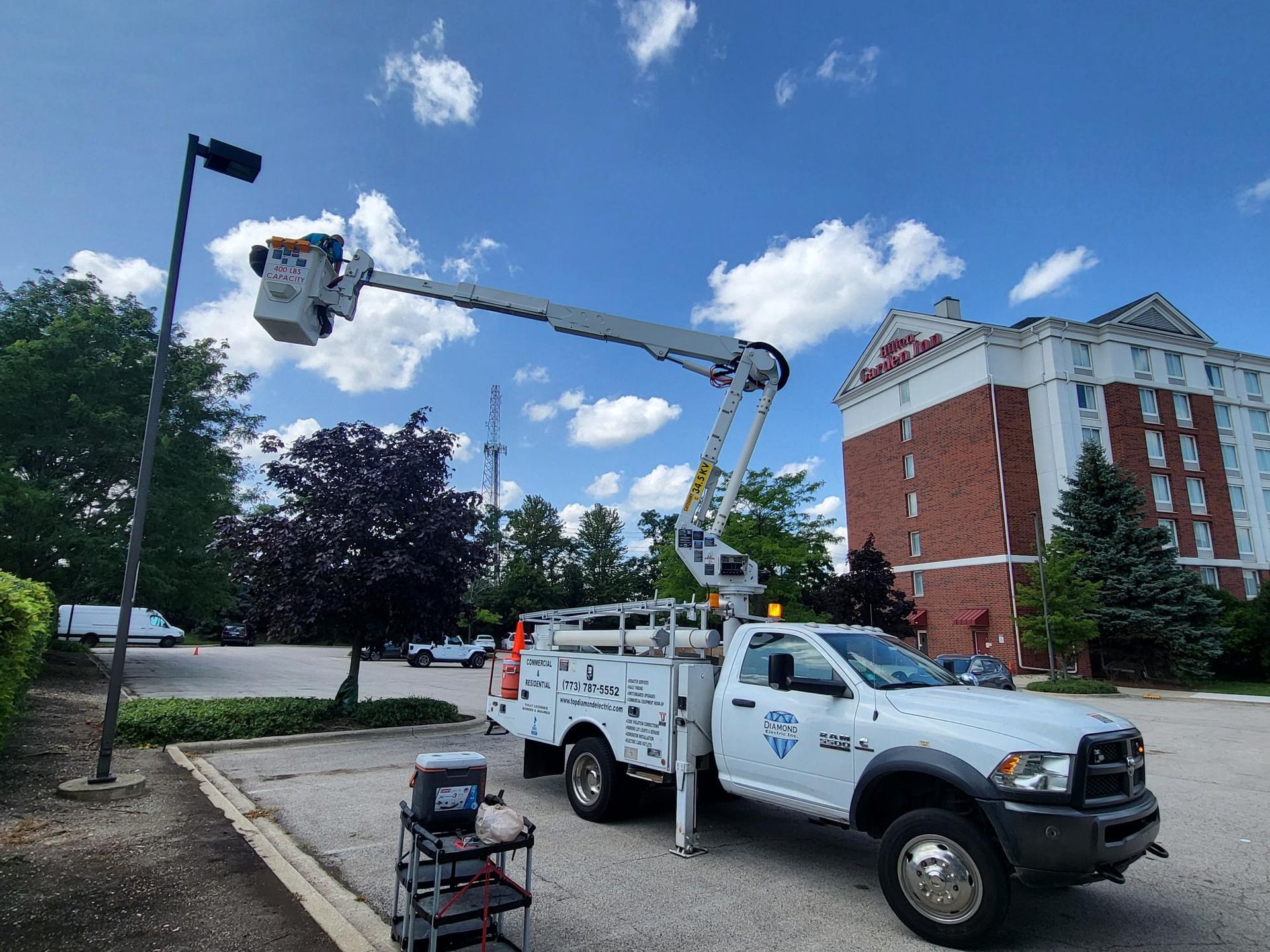 A white truck with a crane on the back is parked in a parking lot.