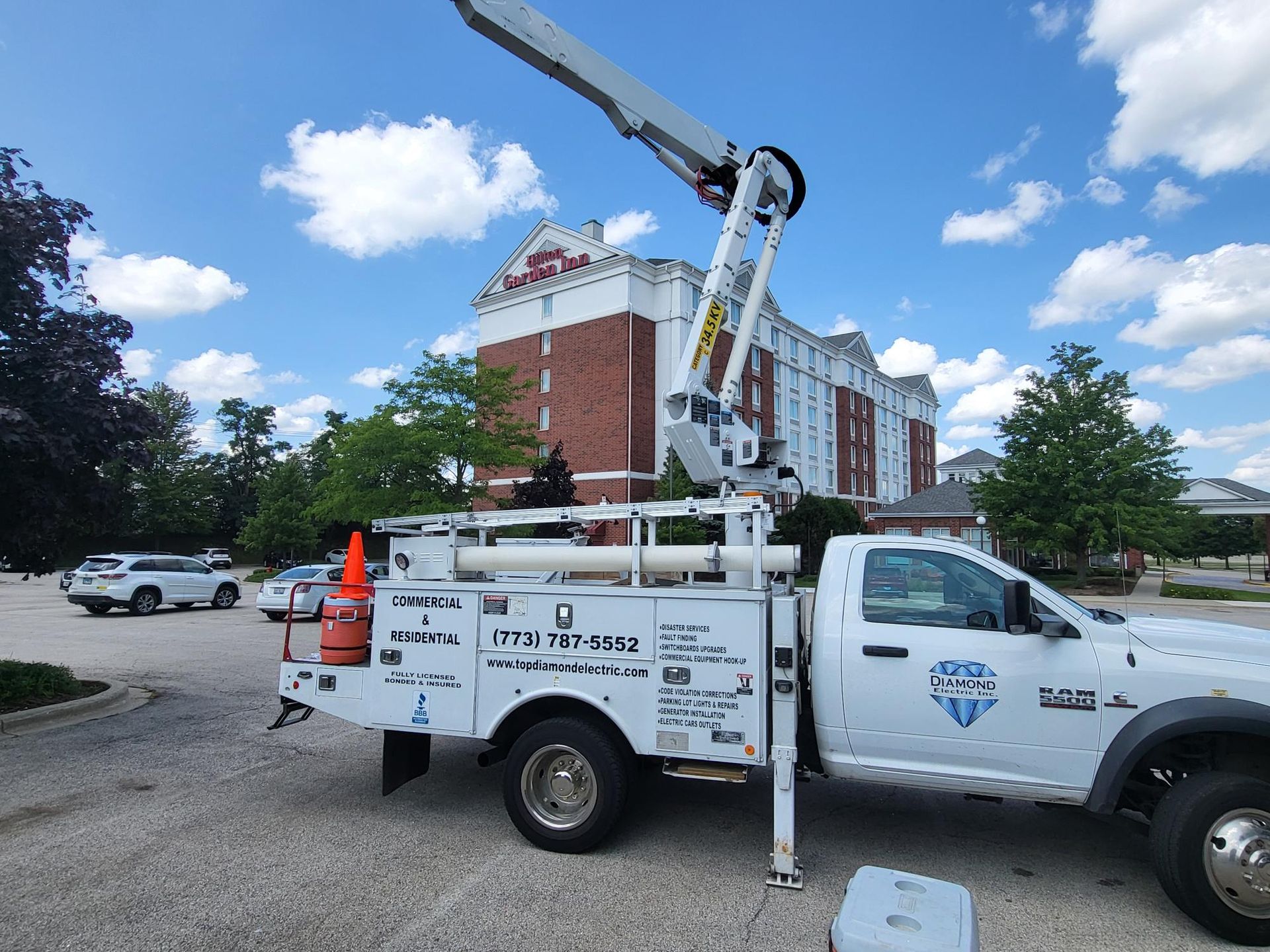 A white truck with a crane on the back is parked in a parking lot