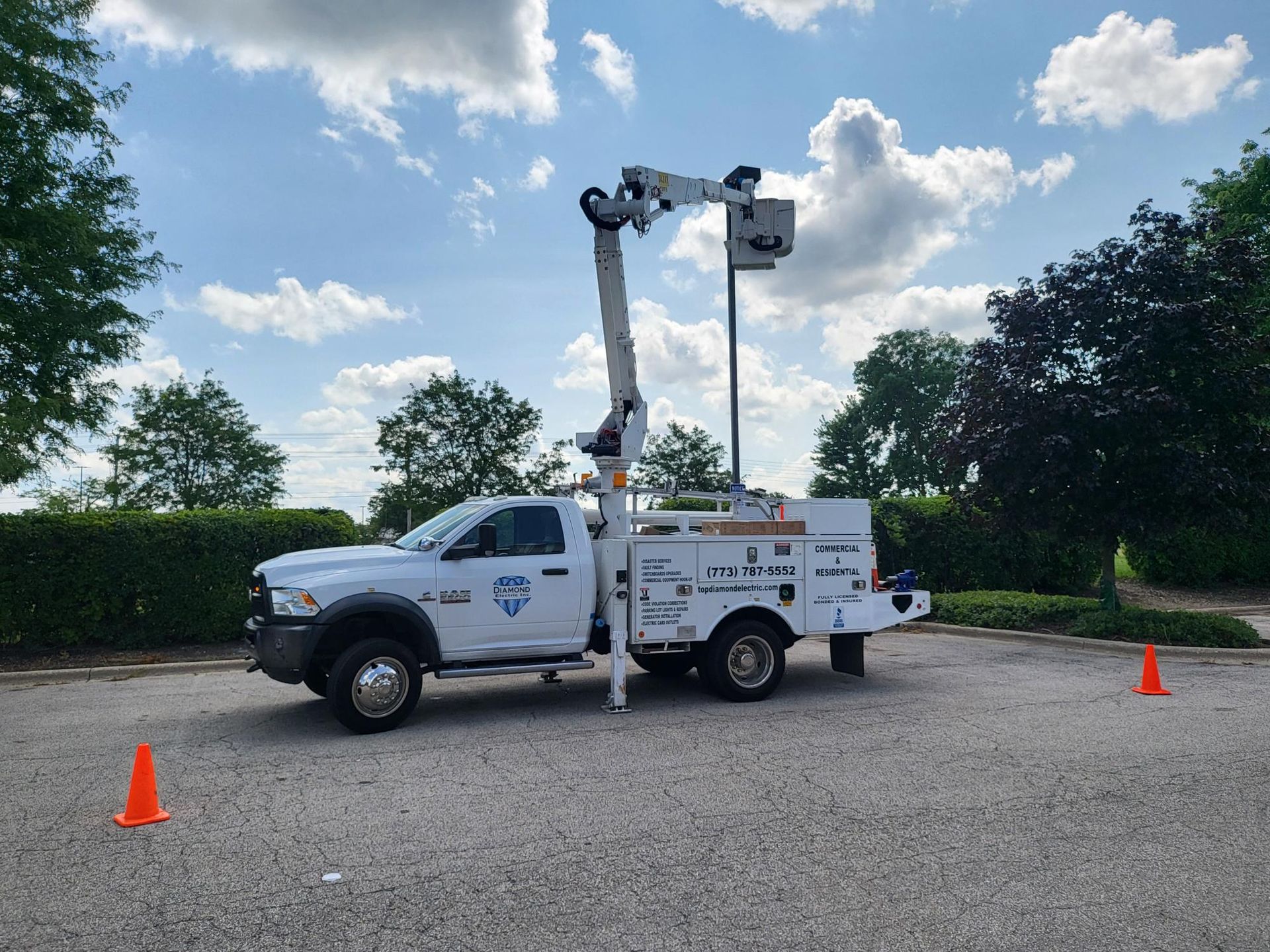 A white truck with a crane on the back is parked in a parking lot