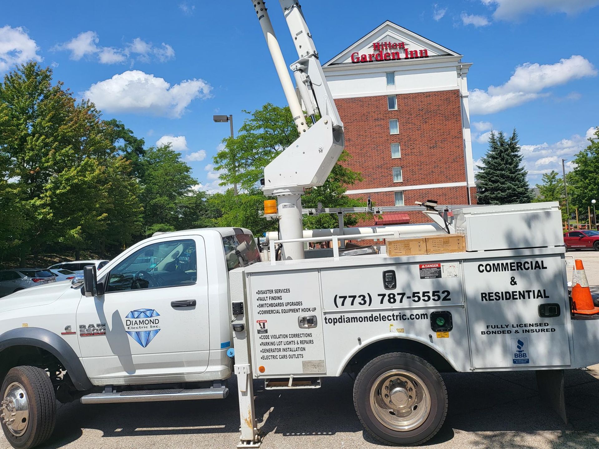 A white truck with a crane on the back is parked in front of a building.