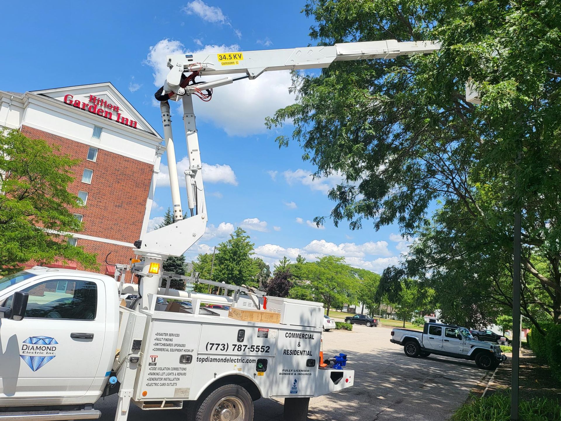 A white truck with a crane on the back is parked in front of a building.