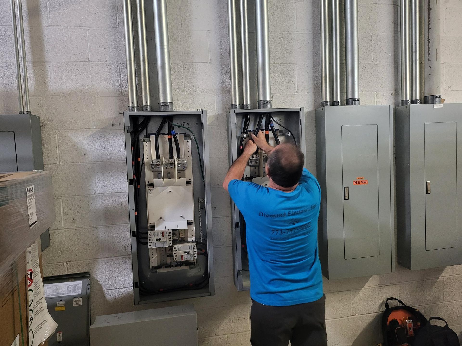 A man in a blue shirt is working on a electrical box.