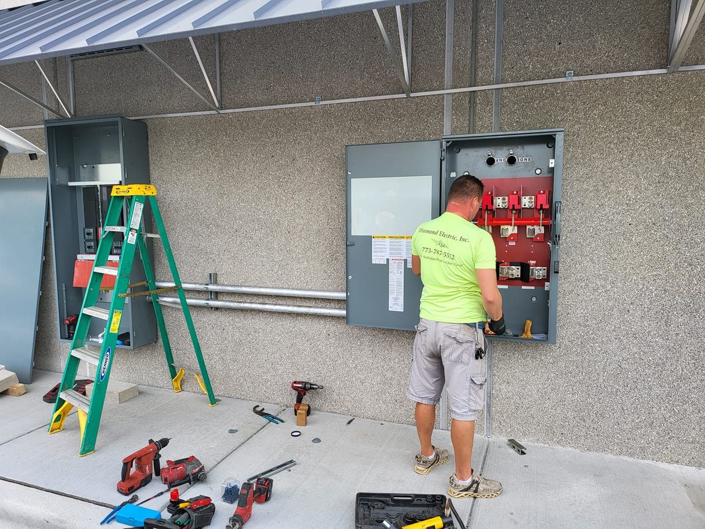 A man is working on an electrical box on the side of a building.