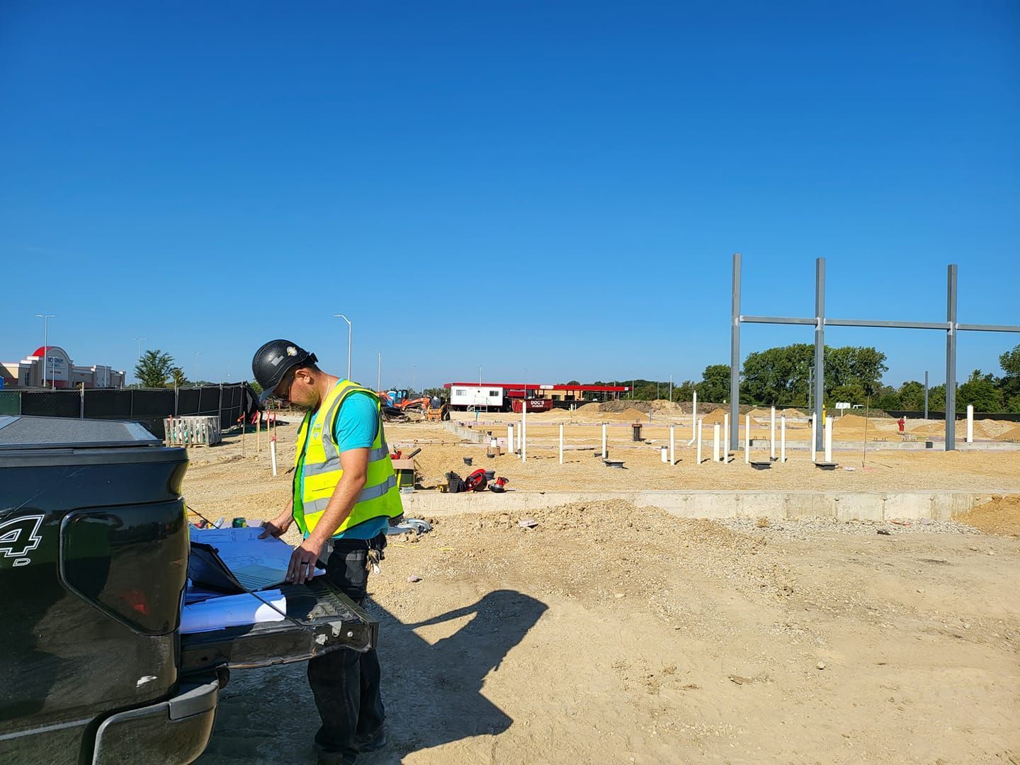A construction worker is standing next to a truck at a construction site.