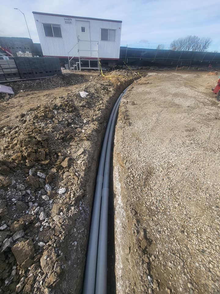 A large pipe is being installed in the dirt in a construction site.