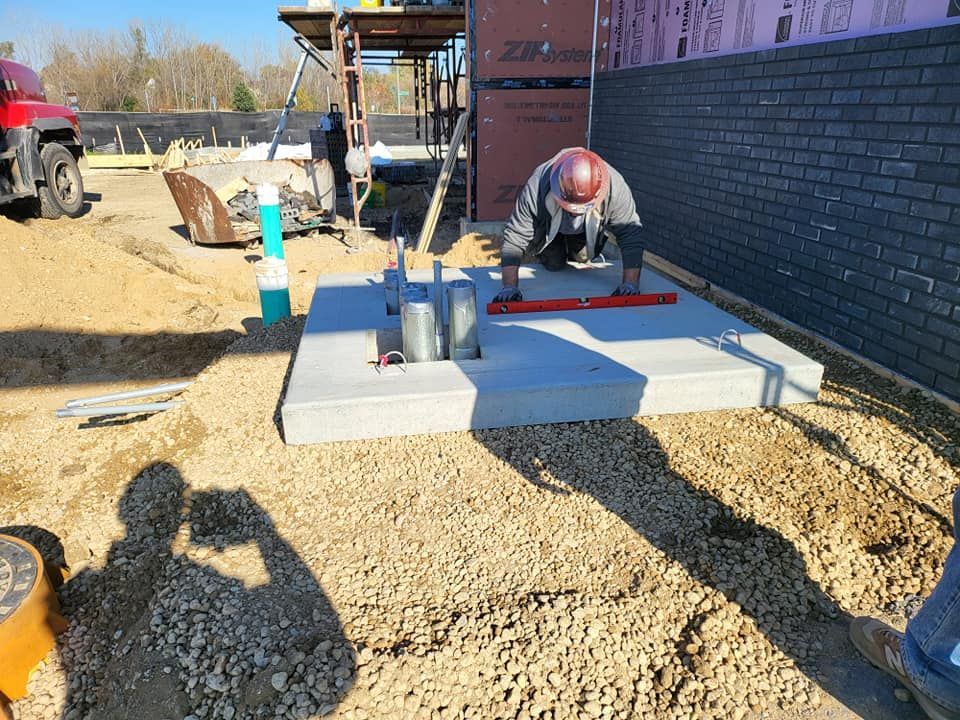 A construction worker is using a level to level a concrete base.