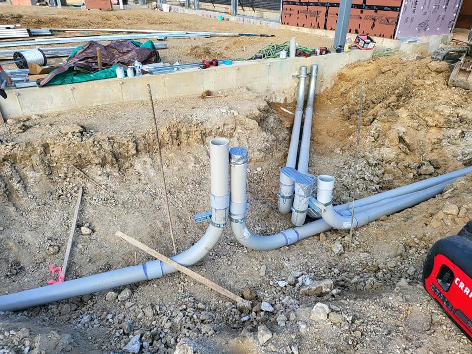 A bunch of pipes are laying in the dirt on a construction site.