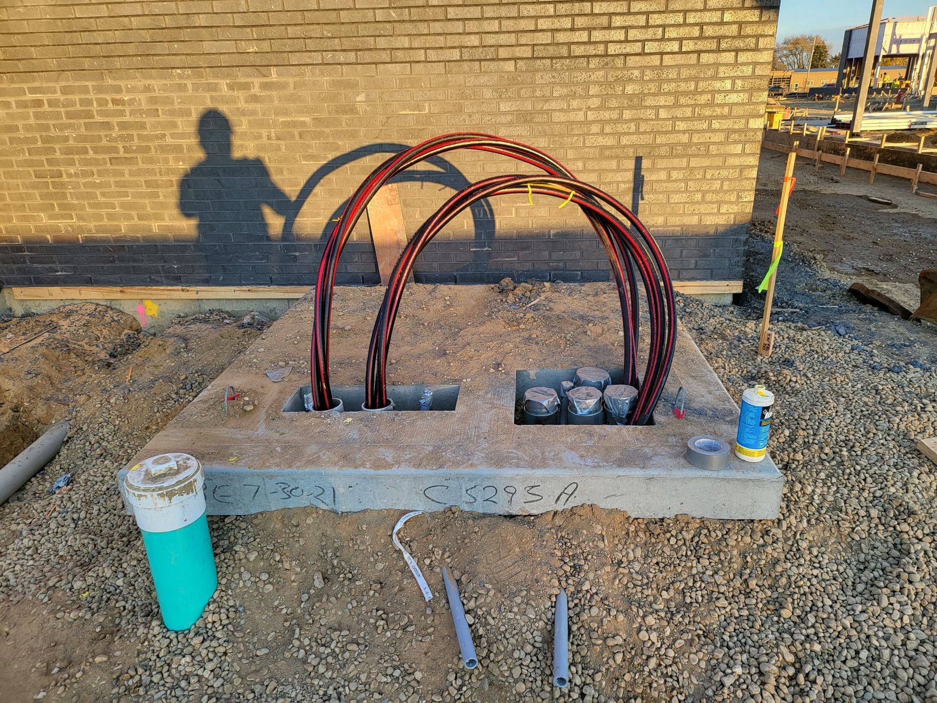 A bunch of wires are sitting on top of a pile of dirt in front of a brick building.