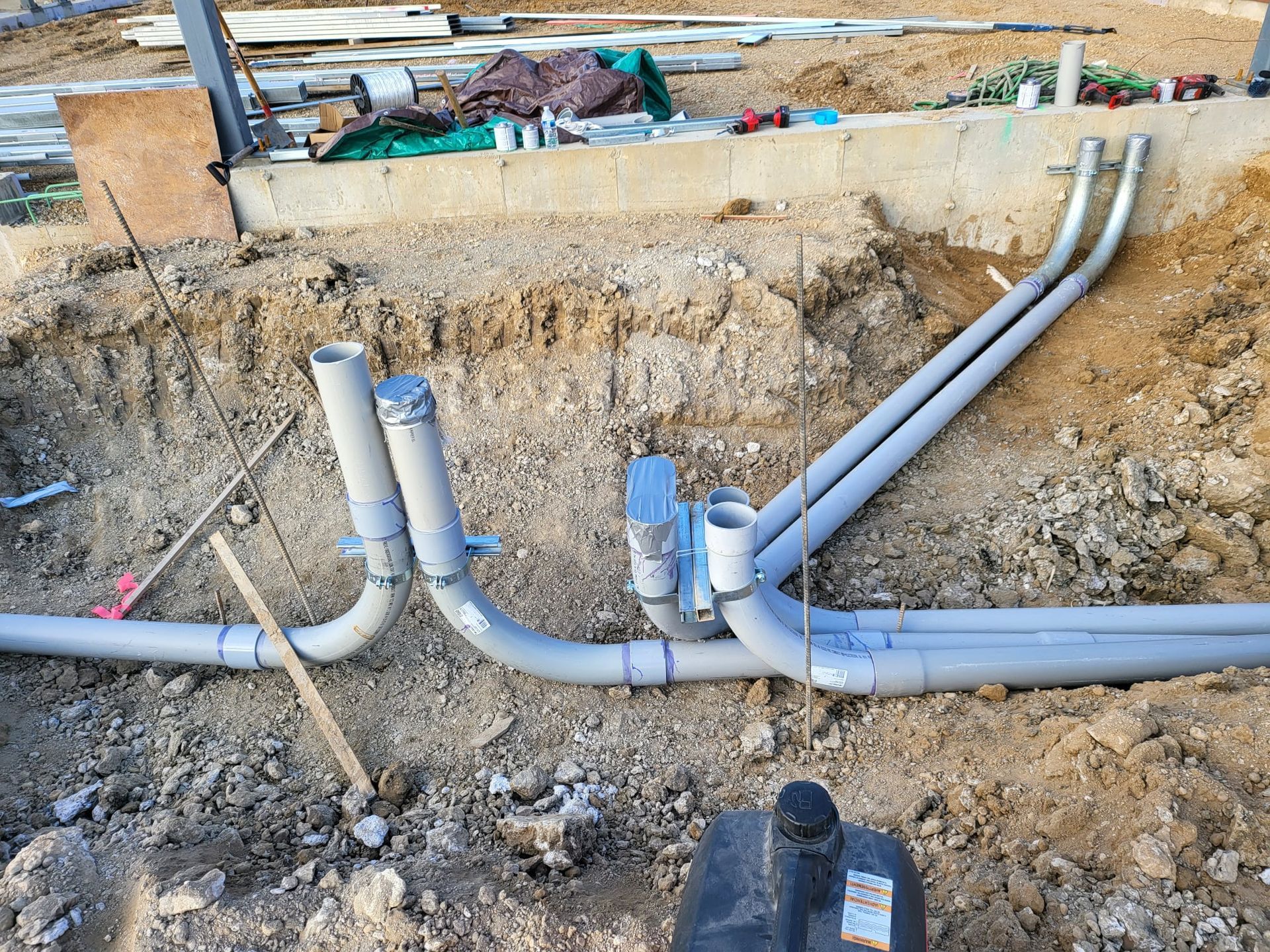 A bunch of pipes are laying in the dirt on a construction site.