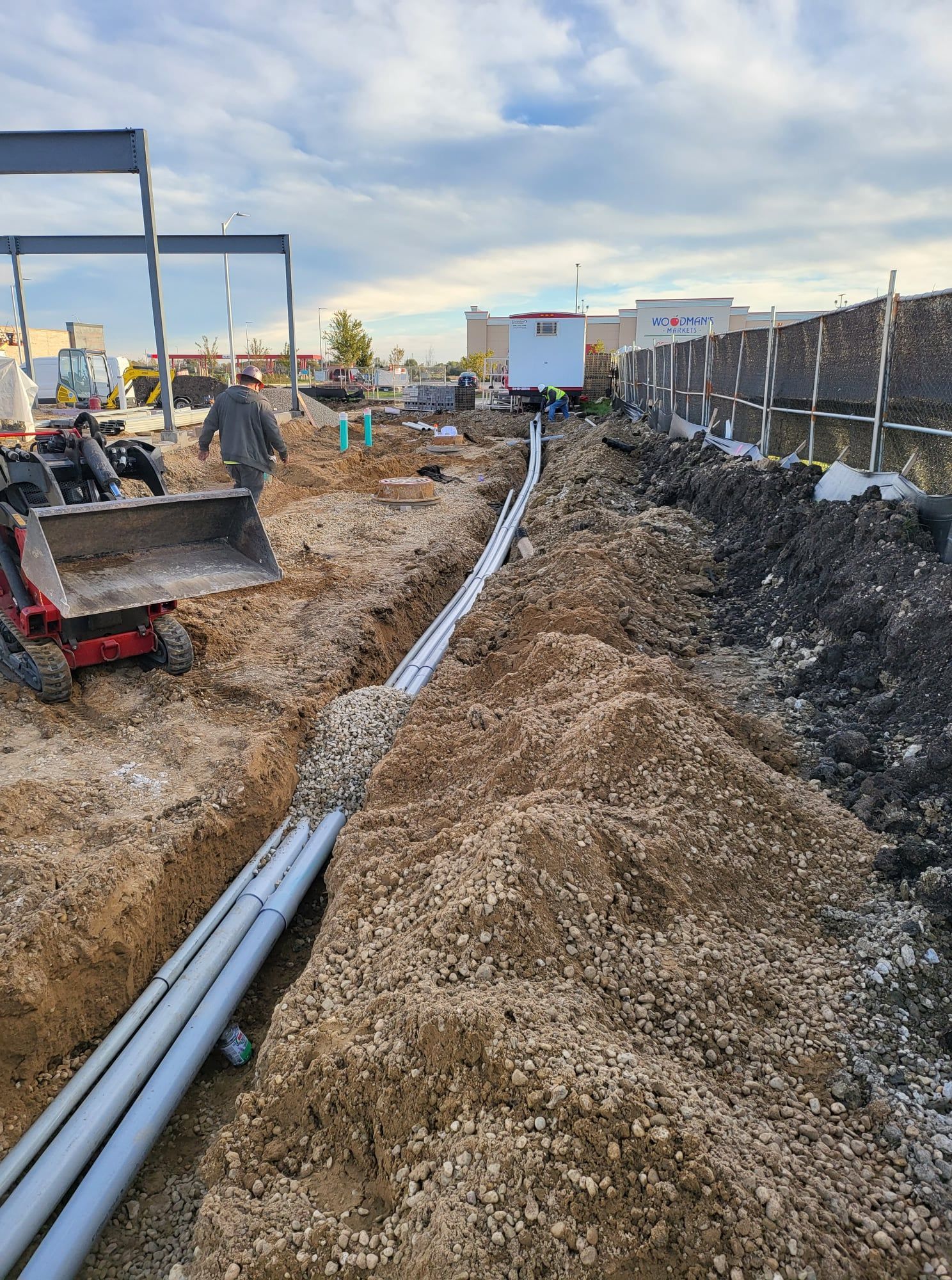 A construction site with a lot of pipes in the dirt.