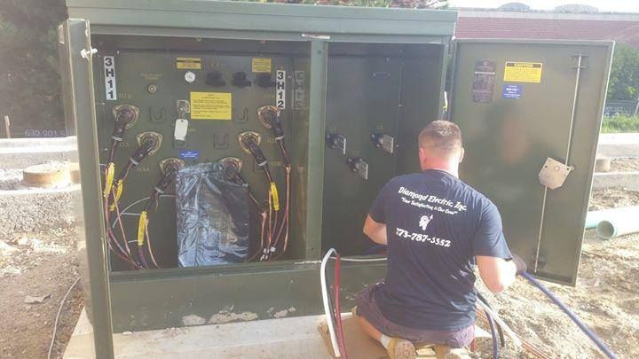 A man is kneeling down in front of a green box.