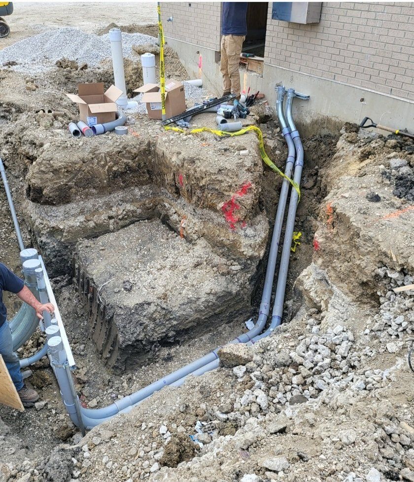 A man is digging a hole in the ground with electrical wires coming out of it.